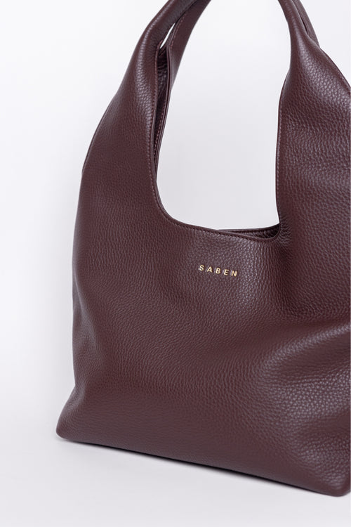 Brown leather handbag with 'SABEN' branding on a white background
