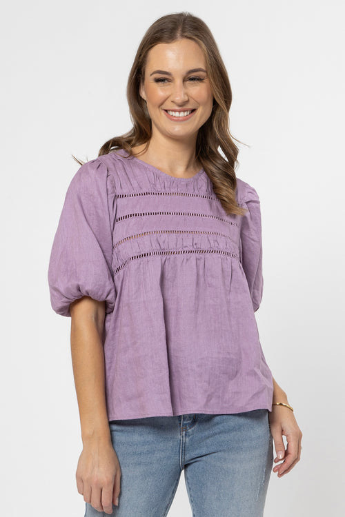 model wears a purple top with jeans