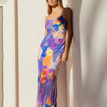 Woman wearing a bias-cut violet floral slip dress with spaghetti straps and abstract flower print.