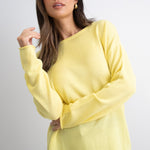 model wears a yellow knit with dark blue jeans