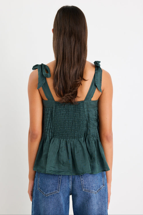 Woman wearing a green cami top and blue jeans