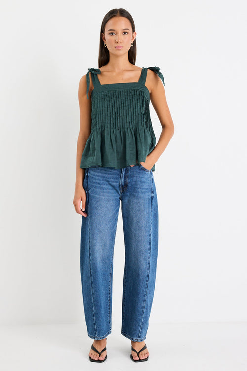 Woman wearing a green cami top and blue jeans