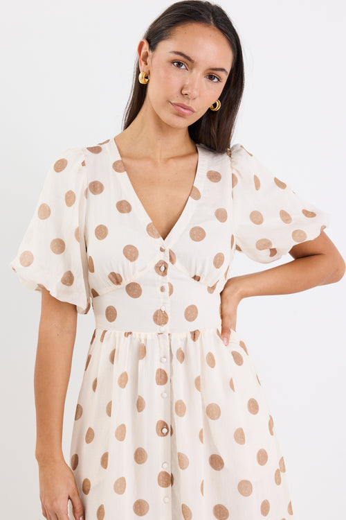 Woman wearing a cream brown polka dot maxi dress