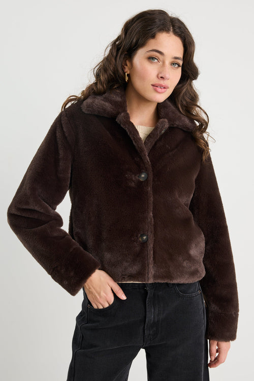 Woman wearing a brown faux fur jacket against a white background