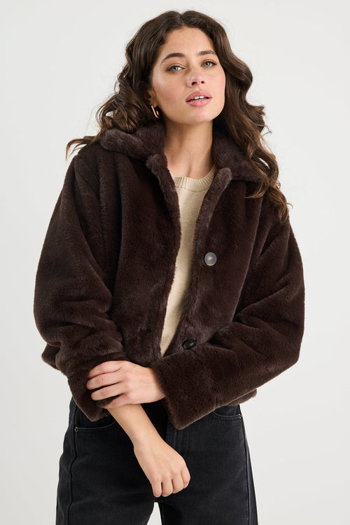 Woman wearing a brown faux fur jacket on a white background