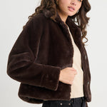 Woman wearing a brown faux fur jacket on a white background