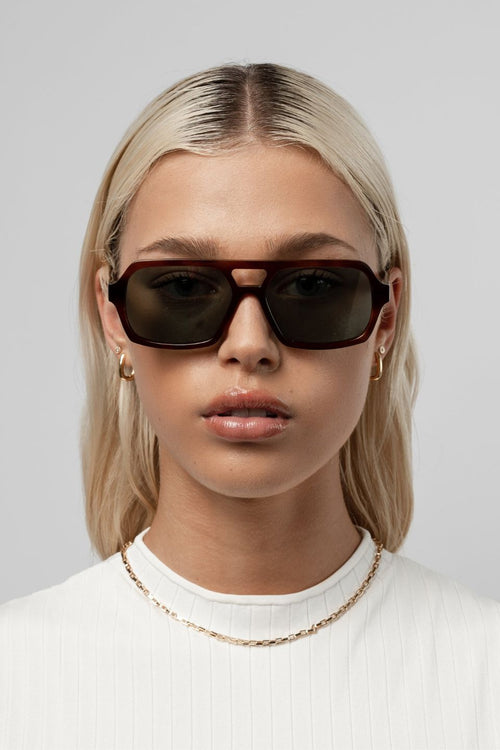 Honey tortoise aviator-style sunglasses with angular frames and green-tinted lenses.