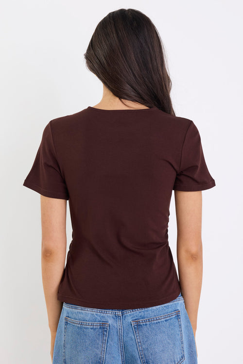 Person wearing a brown t-shirt and blue jeans against a white background