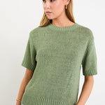Woman wearing a green knitted sweater against a white background