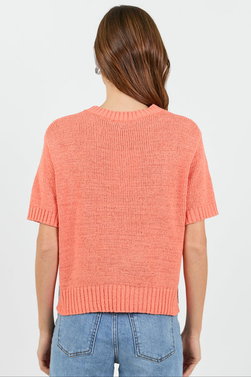 Back of a woman wearing a orange tee and blue jeans on a white background