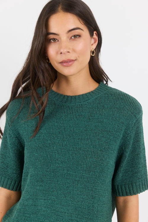 Woman wearing a green knitted sweater against a white background
