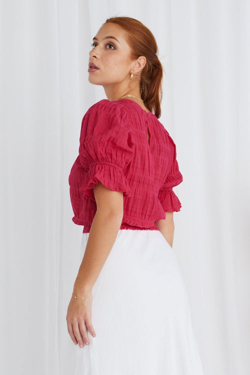 model wears a pink top with white skirt