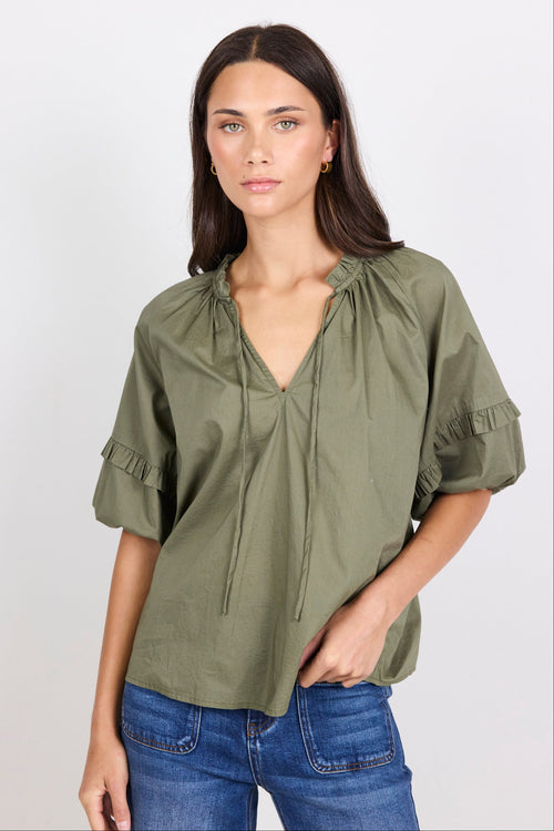 Woman wearing an olive green blouse with a white background