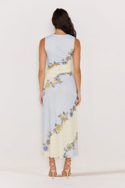 Woman wearing a sleeveless dress with floral pattern on a plain background