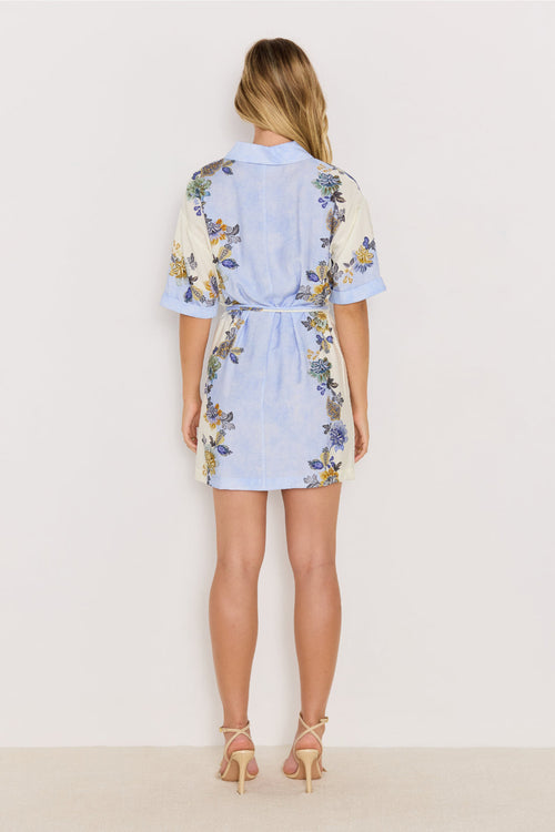 Woman wearing a light blue floral dress on a plain background