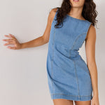 Woman wearing a blue denim dress against a plain background
