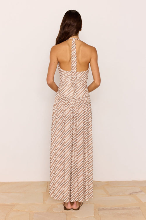 Woman wearing a long, patterned dress against a plain background