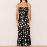 Woman wearing a black floral dress against a plain background