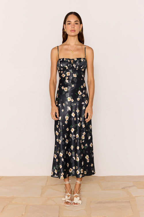 Woman wearing a black floral dress against a plain background