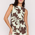 Woman wearing a sleeveless dress with brown floral pattern on a light background
