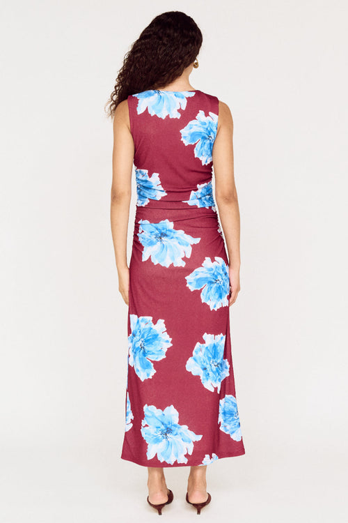 Woman wearing a burgundy dress with blue floral pattern on a white background