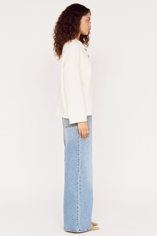 Woman wearing a white blouse and light blue jeans on a white background