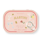 A Paddywax Martini soy wax candle in a pink metal tin with a pull-tab lid, decorated with cocktail glasses, olives, a lemon, and a rose illustration.