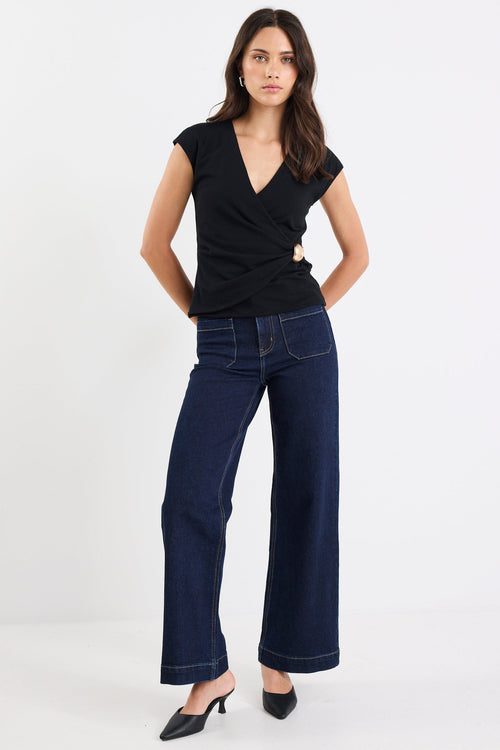 Woman wearing a black top and dark blue jeans on a white background