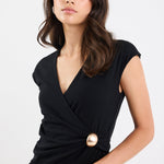 Woman wearing a black top with a gold button on a white background
