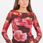 Woman wearing a floral long-sleeve top with a plain background