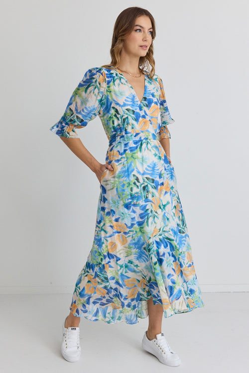 model wears and blue and orange floral maxi dress with white sneakers