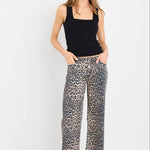 Woman wearing a black tank top and leopard print pants on a white background