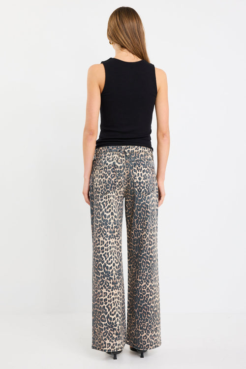 Woman wearing a black sleeveless top and leopard print pants on a white background