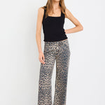 Woman wearing a black sleeveless top and patterned pants on a white background