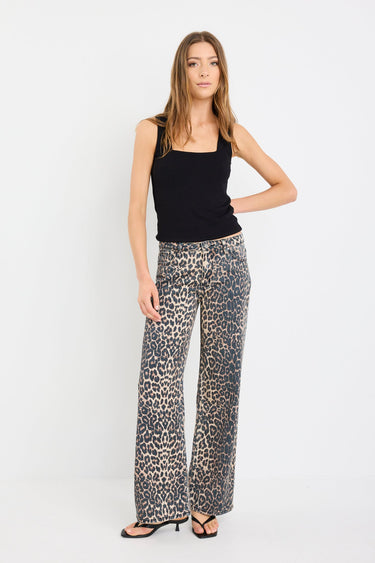 Woman wearing a black sleeveless top and patterned pants on a white background