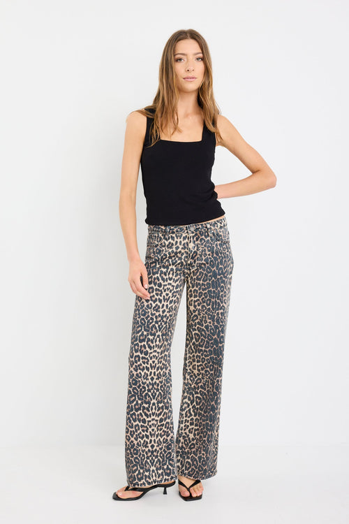 Woman wearing a black sleeveless top and patterned pants on a white background