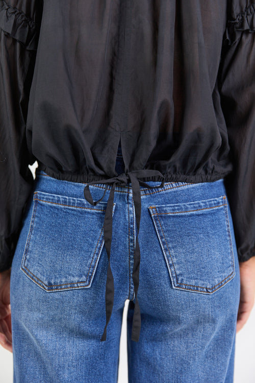 Person wearing a black top and blue jeans.
