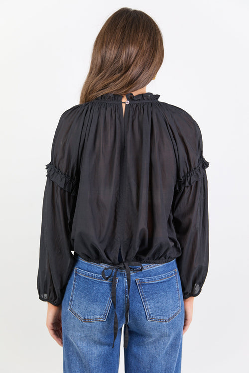 Person wearing a black blouse with long sleeves and blue jeans on a white background