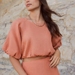 model wears an orange linen top