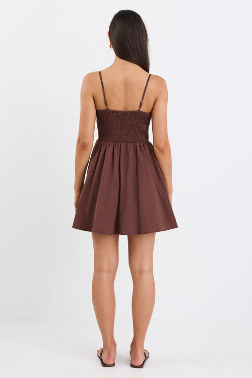 Woman wears a chocolate brown mini dress with pleated bodice