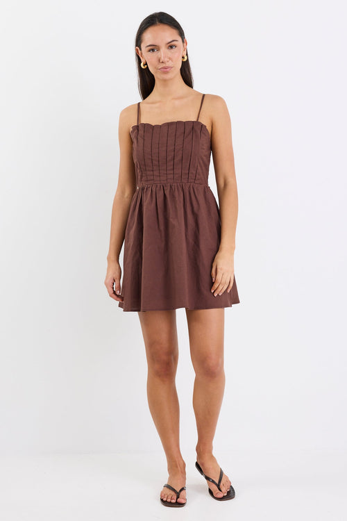Woman wears a chocolate brown mini dress with pleated bodice