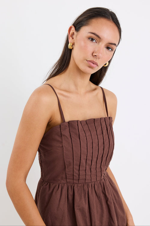 Woman wears a chocolate brown mini dress with pleated bodice