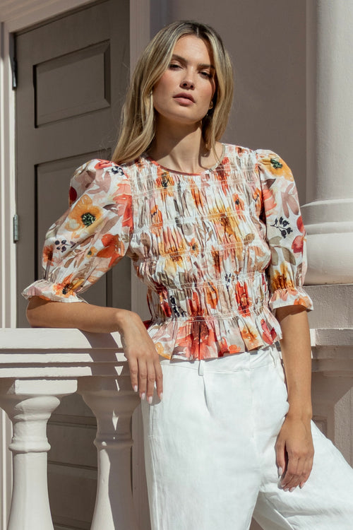 woman wearing a floral shirred short sleeve top with frill sleeves