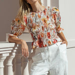 woman wearing a floral shirred short sleeve top with frill sleeves