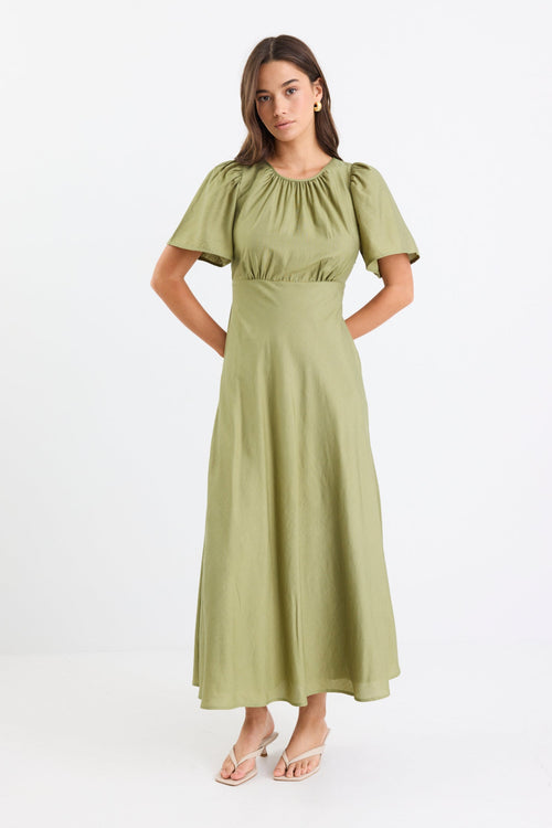 Woman wearing a long green dress with gathering and puff sleeves