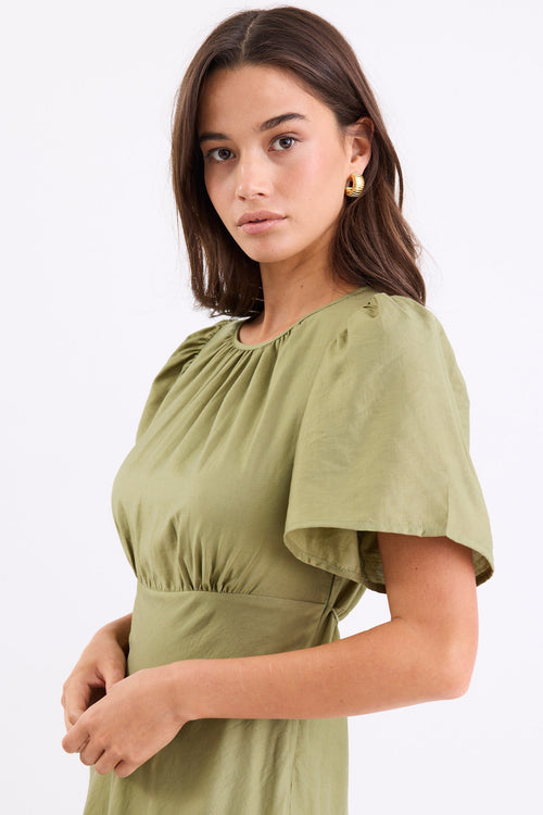 Woman wearing a long green dress with gathering and puff sleeves