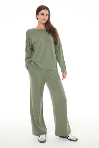 Model wears green lounge pants with a green knit