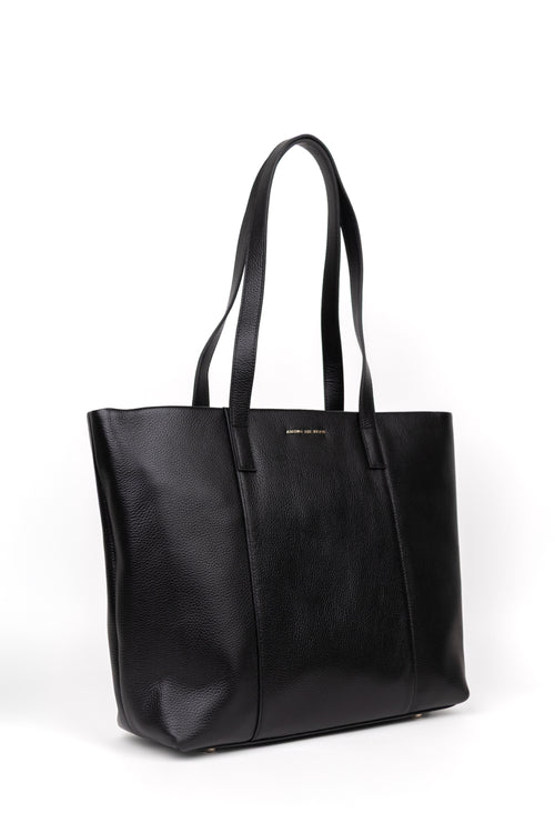 A black pebbled leather tote bag with dual shoulder straps and a small gold logo plaque on the front, photographed on a clean white background.