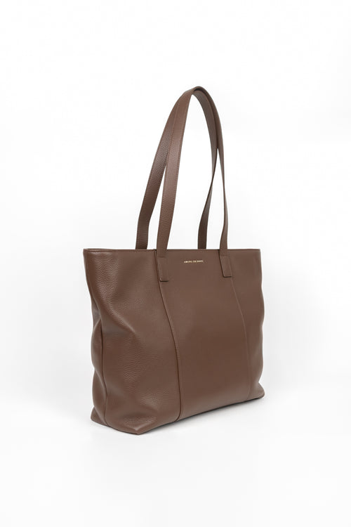 A brown leather tote bag with long shoulder straps, shown from a three-quarter angle on a clean white background.