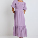 Model wears a dusty lilac shirred tiered maxi dress with puff sleeves 